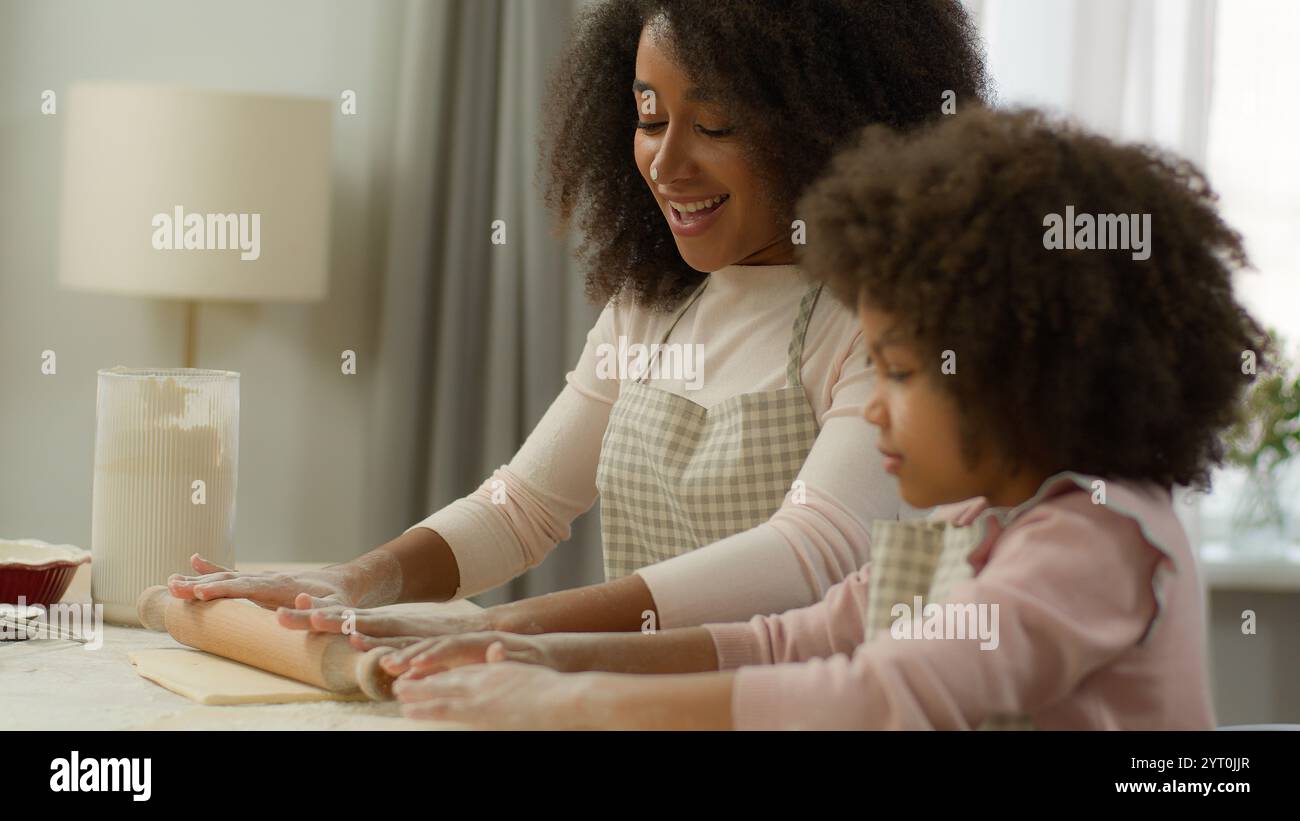 Glückliche Familie in der Küche kocht zusammen lächelnde afroamerikanische Mutter Mutter schmutziges Gesicht in weißem Mehl unterrichtet süße Kind Tochter Vorschule Stockfoto