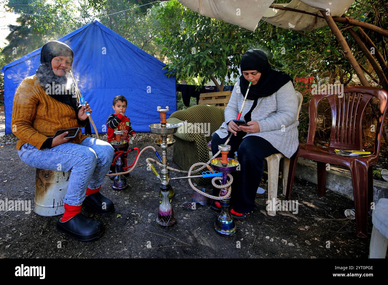 Sidon, Sidon, Libanon. Dezember 2024. Libanesische Dorfbewohner rauchen Huka (Shish) auf dem Hof des Hauses des arabischen Waisenhauses in der südlibanesischen Stadt Sidon. Hundert Dorfbewohner flüchteten das Institut, nachdem sie ihre zerstörten Dörfer, die noch immer von israelischen Truppen besetzt sind, nicht erreichen konnten. Das israelische Militär hat die libanesischen Bürger davor gewarnt, in 60 Dörfer im Süden des Landes zurückzukehren, nachdem mehr als ein Jahr lang ein Waffenstillstand mit der pro-iranischen Hisbollah in Kraft getreten ist. (Kreditbild: © Marwan Naamani/ZUMA Press Wire) NUR REDAKTIONELLE VERWENDUNG! Nicht für Comme Stockfoto