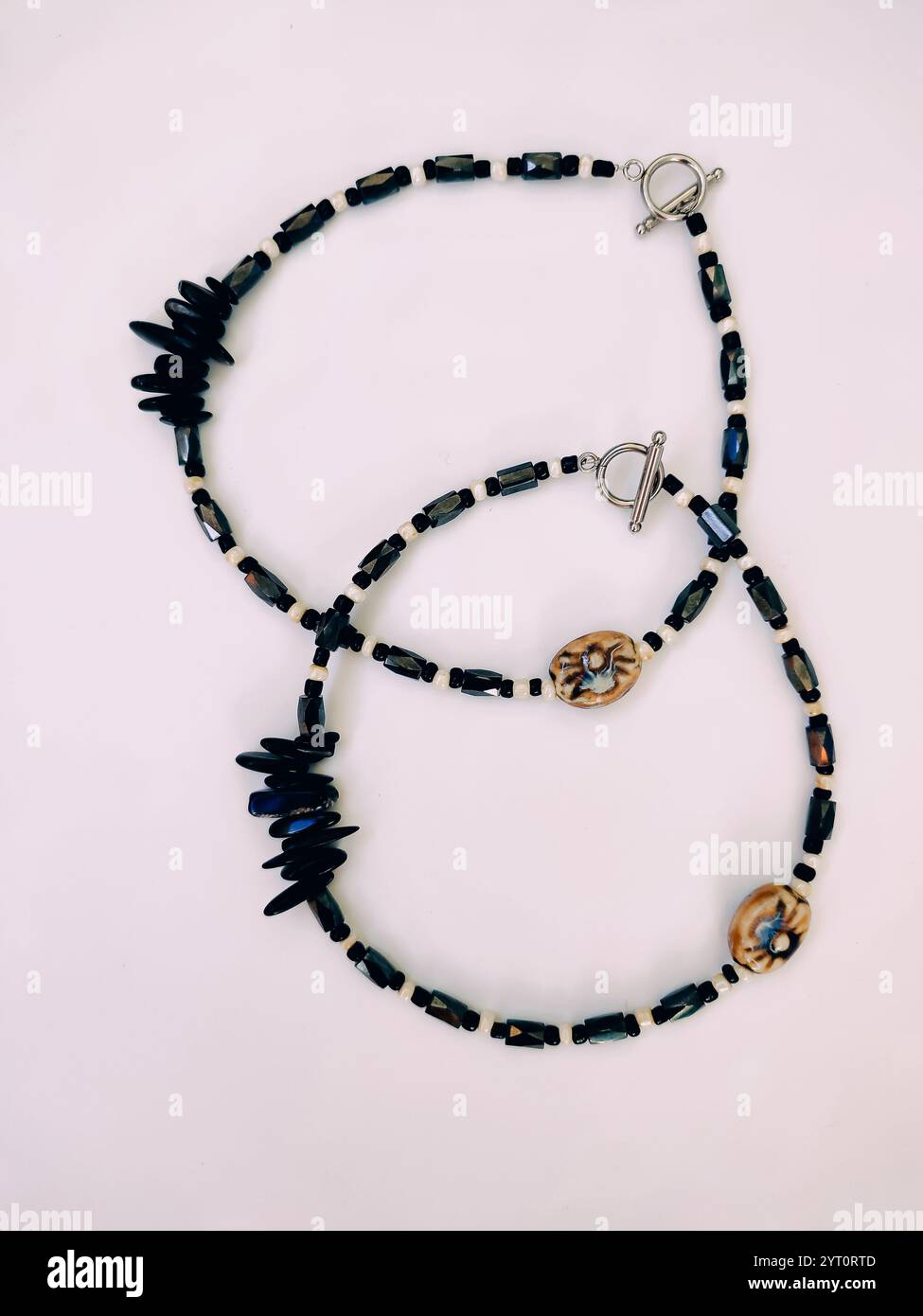 Paar Halsketten mit schwarzen Steinperlen auf rosa Hintergrund aus nächster Nähe von oben. Hämatit, Magnetit Halbedelstein Choker, unregelmäßige Form Stockfoto