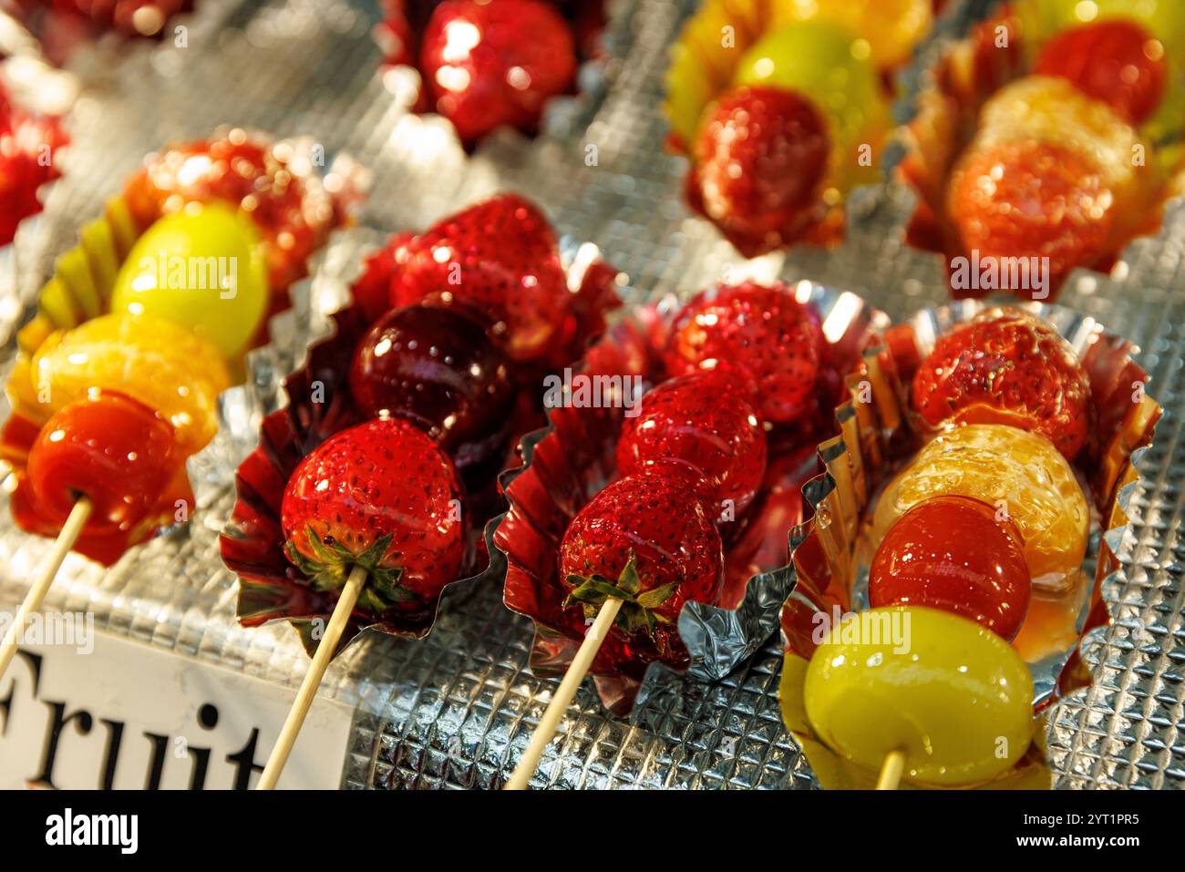 Genießen Sie lebendige, farbenfrohe Spieße mit köstlich glasierten Früchten, die ideal für Street Food-Fans und festliche Veranstaltungen sind Stockfoto