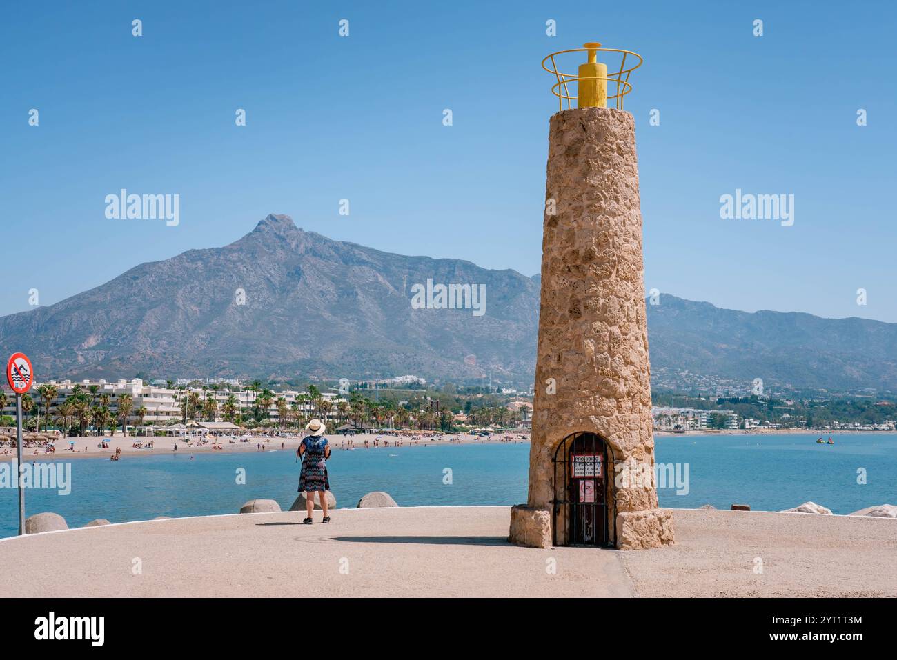 Weibliche Touristen, die die Sommerferien genießen und den Blick auf das Mittelmeer und die Berge in der Nähe eines Leuchtturms in Marbella, Spanien, bewundern Stockfoto