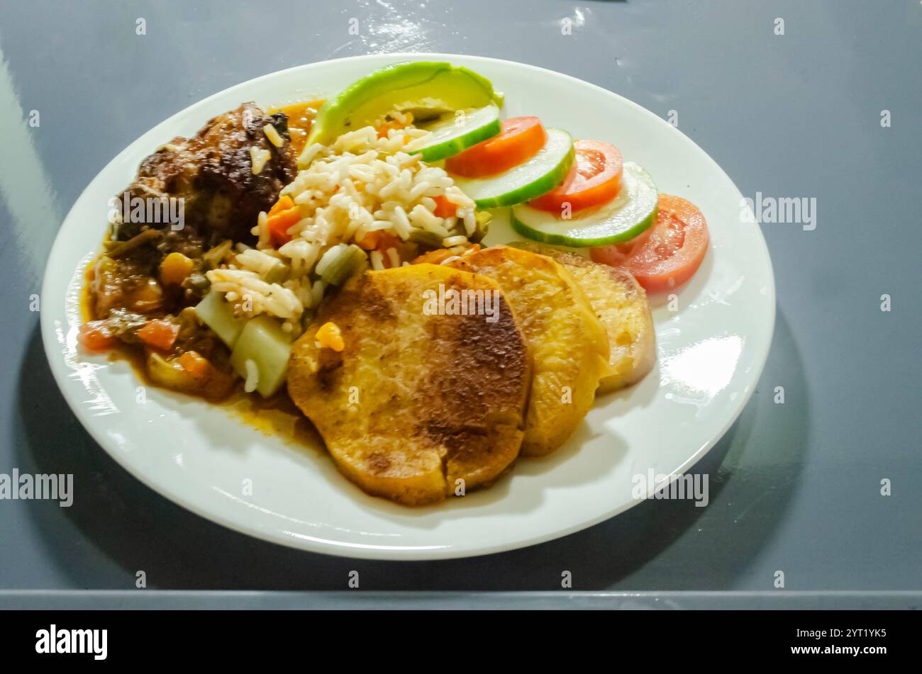 Ein Gericht bestehend aus kandierten Süßkartoffeln, Rise, Bohnen, Karotten, Huhn, Tomaten, Gurken und Avocado stehen auf einem Tablett. Stockfoto