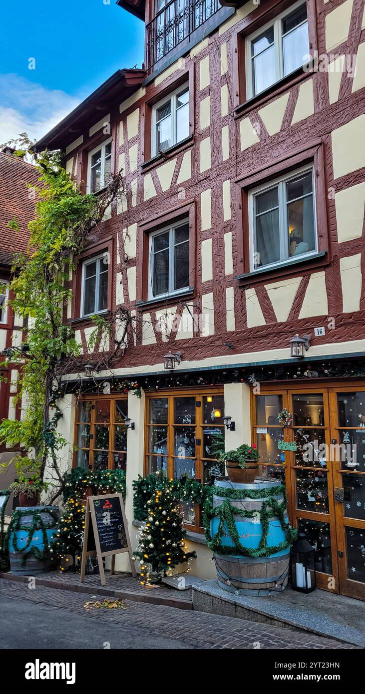 Charmantes mittelalterliches Meersburg vor Weihnachten. Blick auf ein wunderschönes Fachwerkhaus mit einem Geschäft, dekoriert mit Weihnachtsschmuck und Girlanden Stockfoto