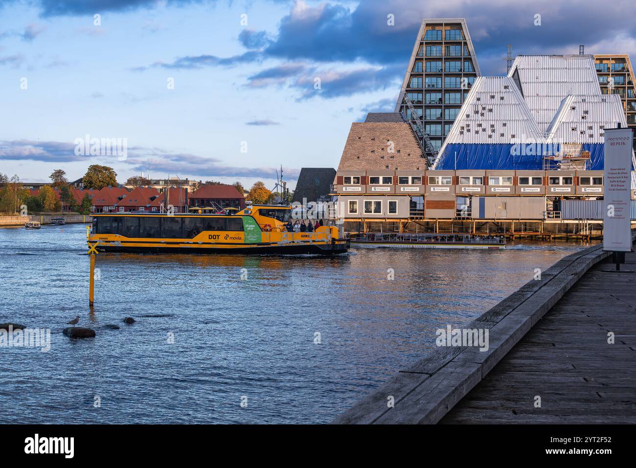 Kopenhagen, Dänemark - 6. Oktober 2024: Eine lebhafte gelbe Fähre fährt über Kopenhagens ruhige Wasserstraße unter teilweise bewölktem Himmel Stockfoto