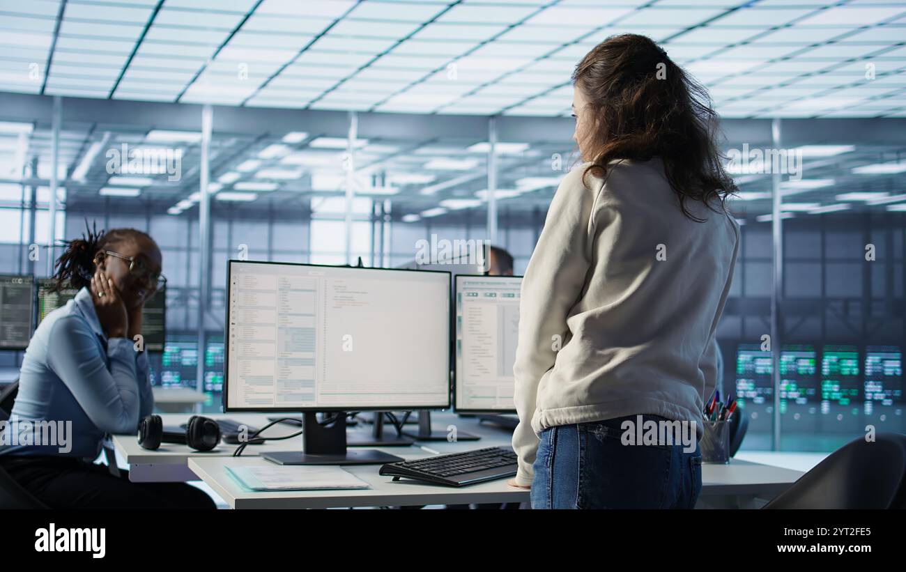 Manager leitet multiethnische Teams, die im Rechenzentrum arbeiten und Ankündigungen machen. Teamleiter bespricht mit Mitarbeitern die Überwachung des Energieverbrauchs über die Komponenten von Serveranlagen hinweg, Kamera B Stockfoto