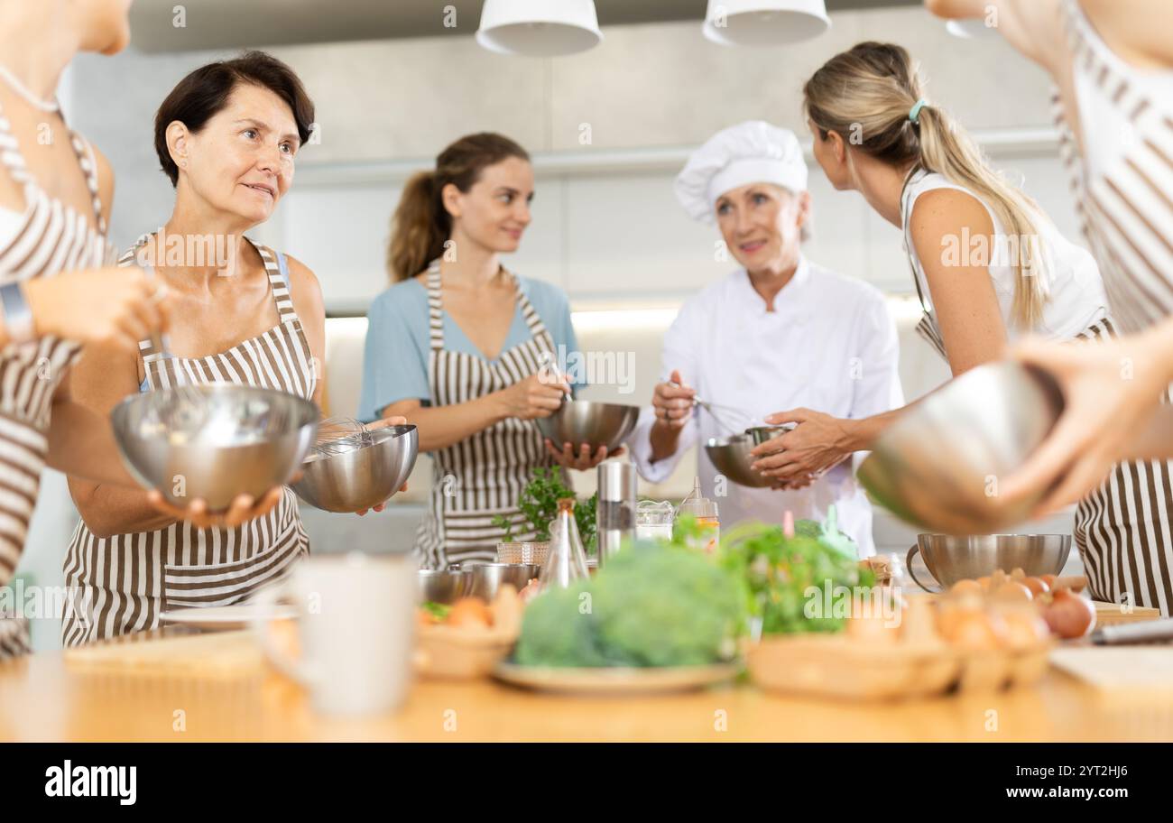 Ältere weibliche Besucherin unterhalten sich mit einer Person, die mit einem Freund auf kulinarischen Kursen konfrontiert ist Stockfoto