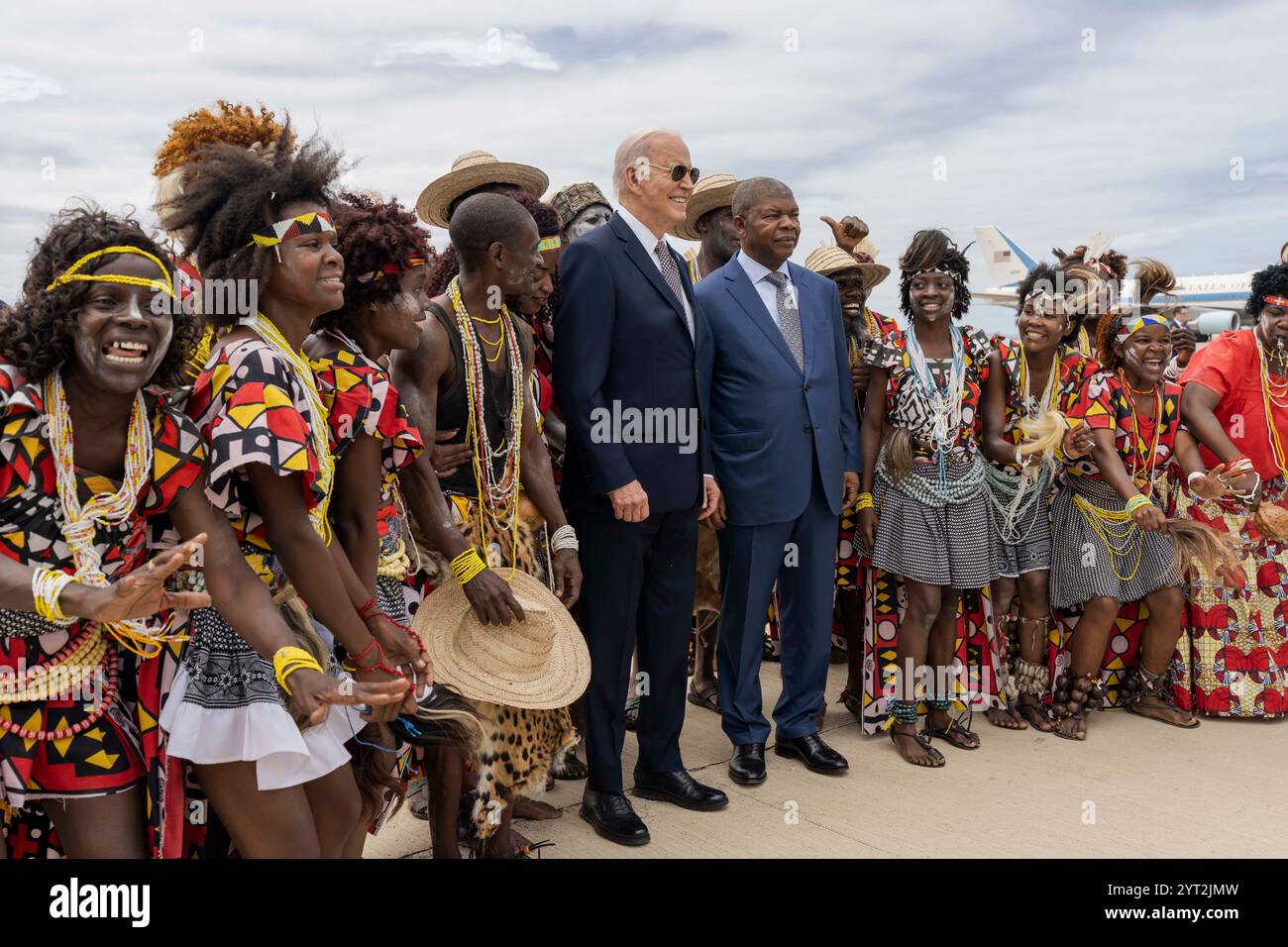 Lobito, Angola. Dezember 2024. US-Präsident Joe Biden, Center, und angolanischer Präsident Joao Lourenco, rechts, posieren mit Mitgliedern einer traditionellen Tanzgruppe bei der Ankunft zum Lobito Corridor Trans-Africa Summit am Catumbela International Airport, 4. Dezember 2024 in Lobito, Angola. Quelle: Cameron Smith/White House Photo/Alamy Live News Stockfoto