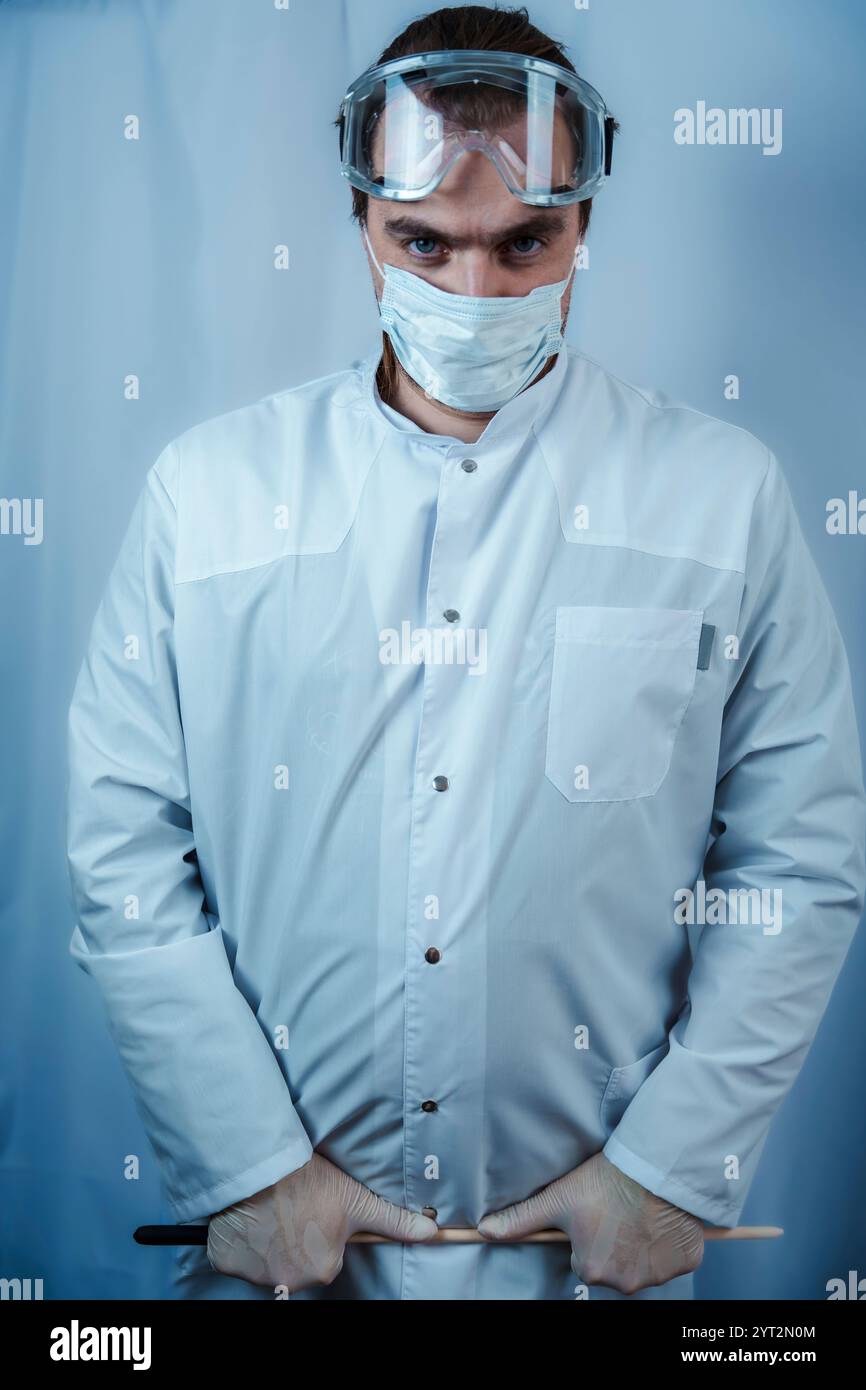 Ein Wissenschaftler hält ein mit bunten Flüssigkeiten gefülltes Reagenzglas in einem Labor, umgeben von verschiedenen wissenschaftlichen Geräten, sorgfältig in der Hand. Das Bild wird hervorgehoben Stockfoto