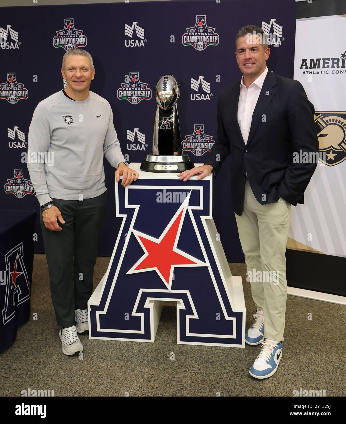 West Point, New York, USA. Dezember 2024. Kommissar TIM PERNETTI von der American Athletic Conference und Chef der Army Black Knights JEFF MONKEN posieren mit der Meisterschafttrophäe bei der Pressekonferenz vor dem Spiel für die American Athletic Conference Football Championship auf dem Campus der Army Black Knights in West Point. (Kreditbild: © Scott Rausenberger/ZUMA Press Wire) NUR REDAKTIONELLE VERWENDUNG! Nicht für kommerzielle ZWECKE! Stockfoto