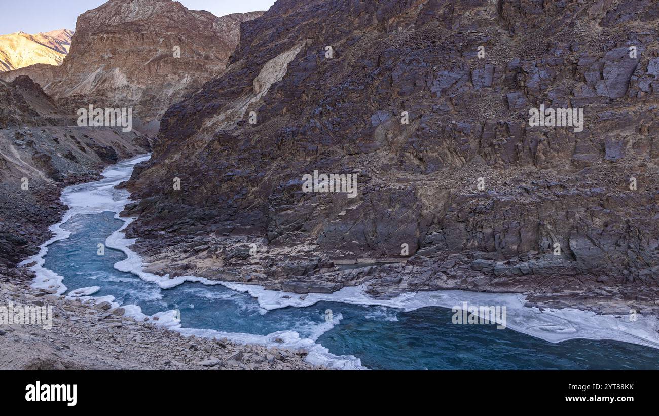 Blaues Wasser des Zanskar-Flusses, das im Winter an den Seiten gefrorenen ist und durch Berge fließt. Stockfoto