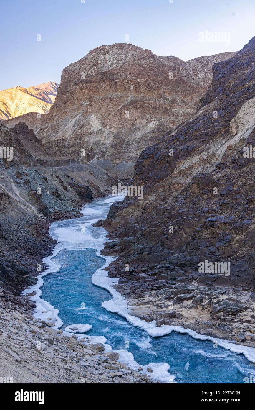 Blaues Wasser des Zanskar-Flusses, das im Winter an den Seiten gefrorenen ist und durch Berge fließt. Stockfoto