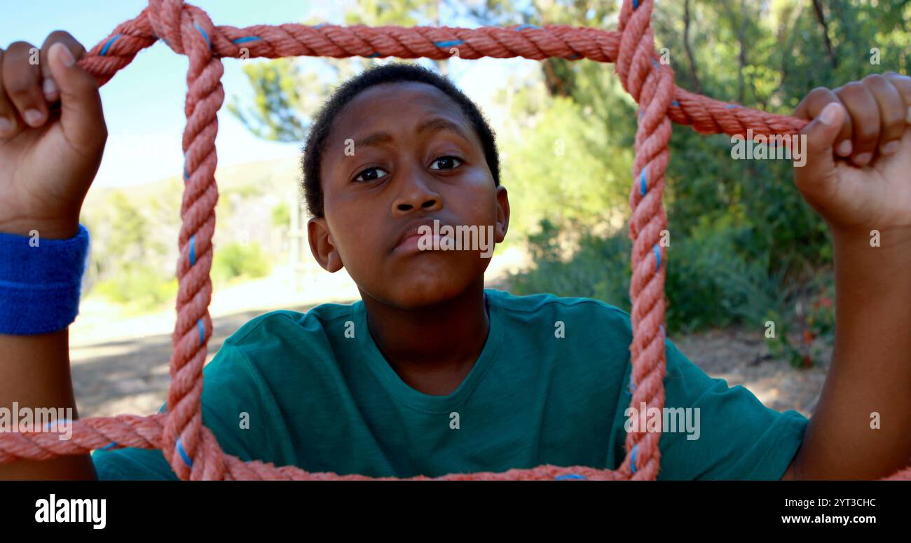 Müder Junge, der sich auf das Netz stützt während des Hinderniskurses im Bootcamp Stockfoto