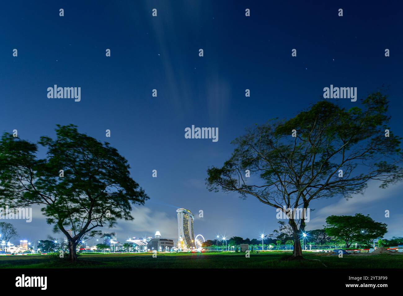 Nächtliche Landschaft und Marina Bay Sands, lange Exposition, Sterne und Wind im Himmel. Große Bäume. Sternenhimmel in Singapur. Stockfoto