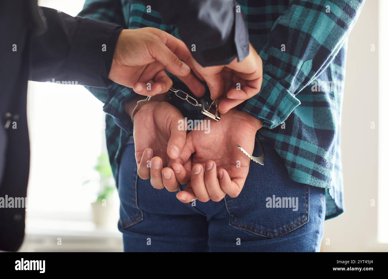 Polizist, Polizist, der die Verhaftung des Schuldigen vornimmt und bearbeitet, Handschellen an den Manakeln befestigt Stockfoto