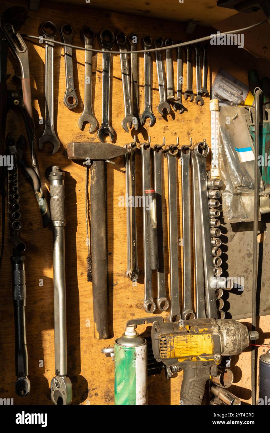 Ein gut organisiertes Holzgestell zeigt wichtige Werkzeuge für die Autoreparatur in einer Autowerkstatt und zeigt einen professionellen Arbeitsplatz, der Effizienz verkörpert Stockfoto