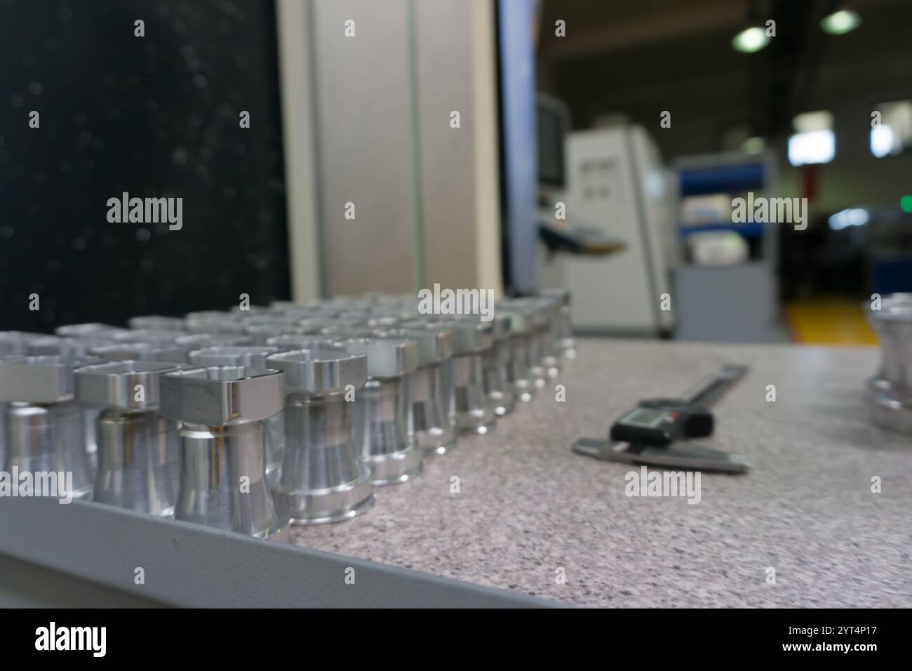 CNC-bearbeitete Metallteile auf Prüftisch und digitalem Messschieber. Industrieszene, Inspektionstabelle im Hintergrund einer Fertigungsanlage Stockfoto