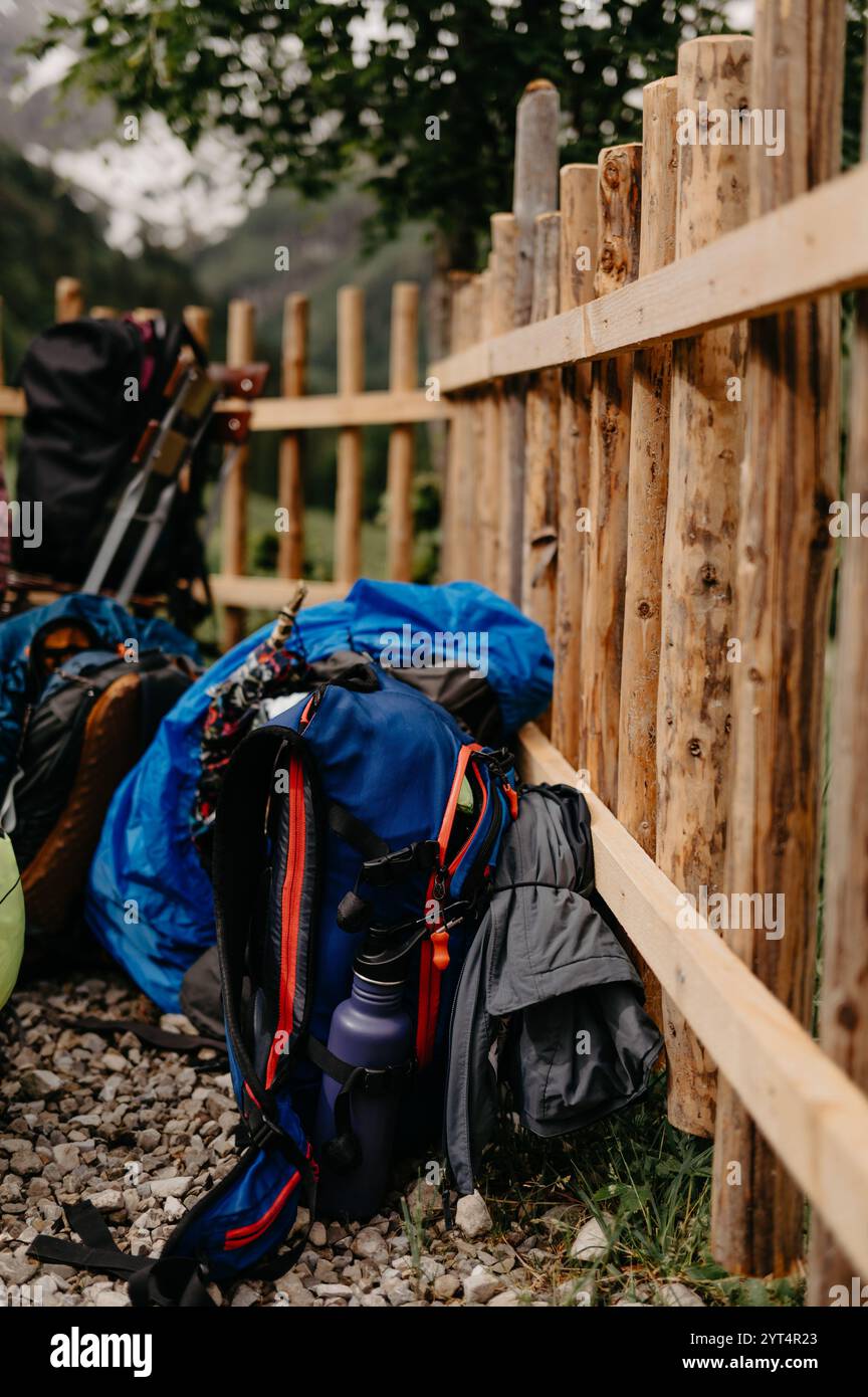 Blaue Wanderrucksäcke mit Wasserflasche vor dem rustikalen Bergzaun Stockfoto