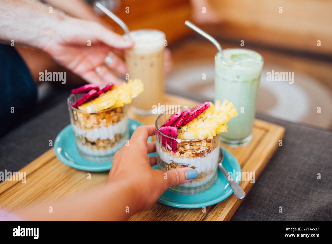 Hände, die nach tropischem Fruchtgranola mit Latte greifen Stockfoto