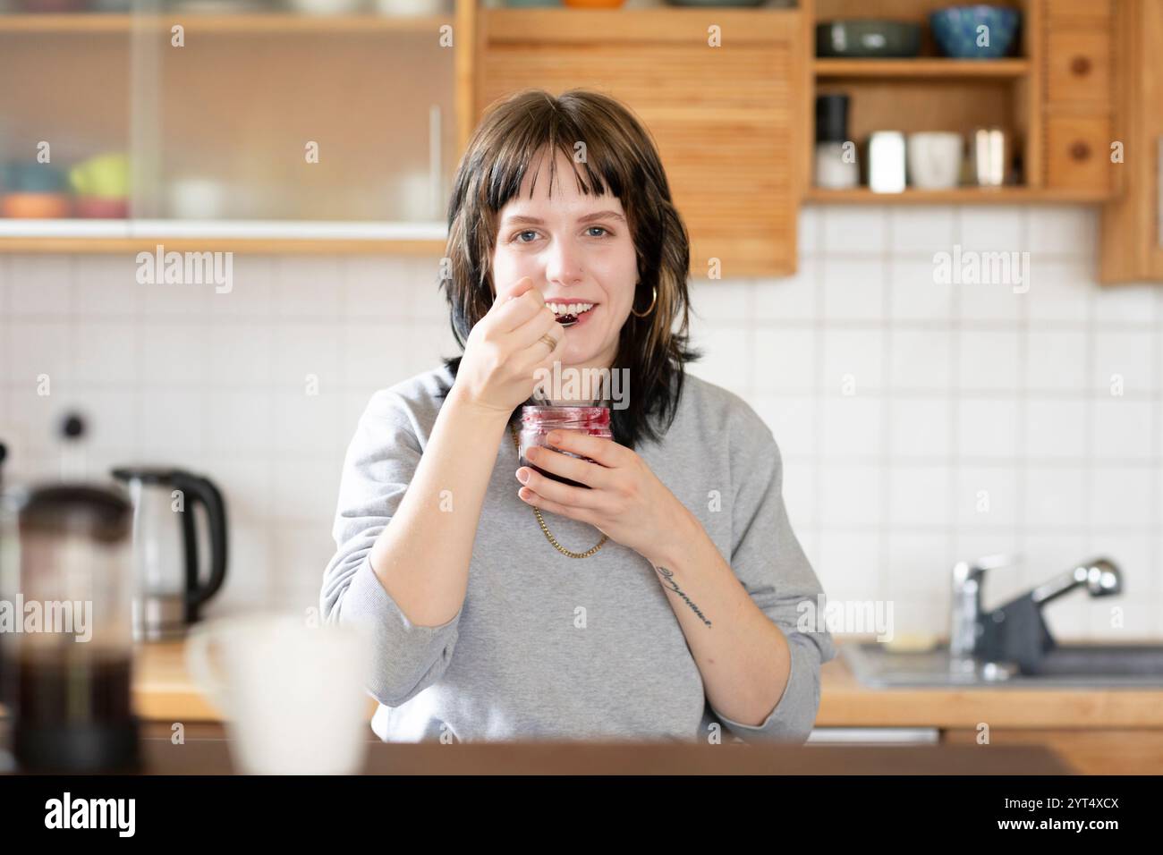 Eine junge Frau isst Marmelade in der Küche Stockfoto