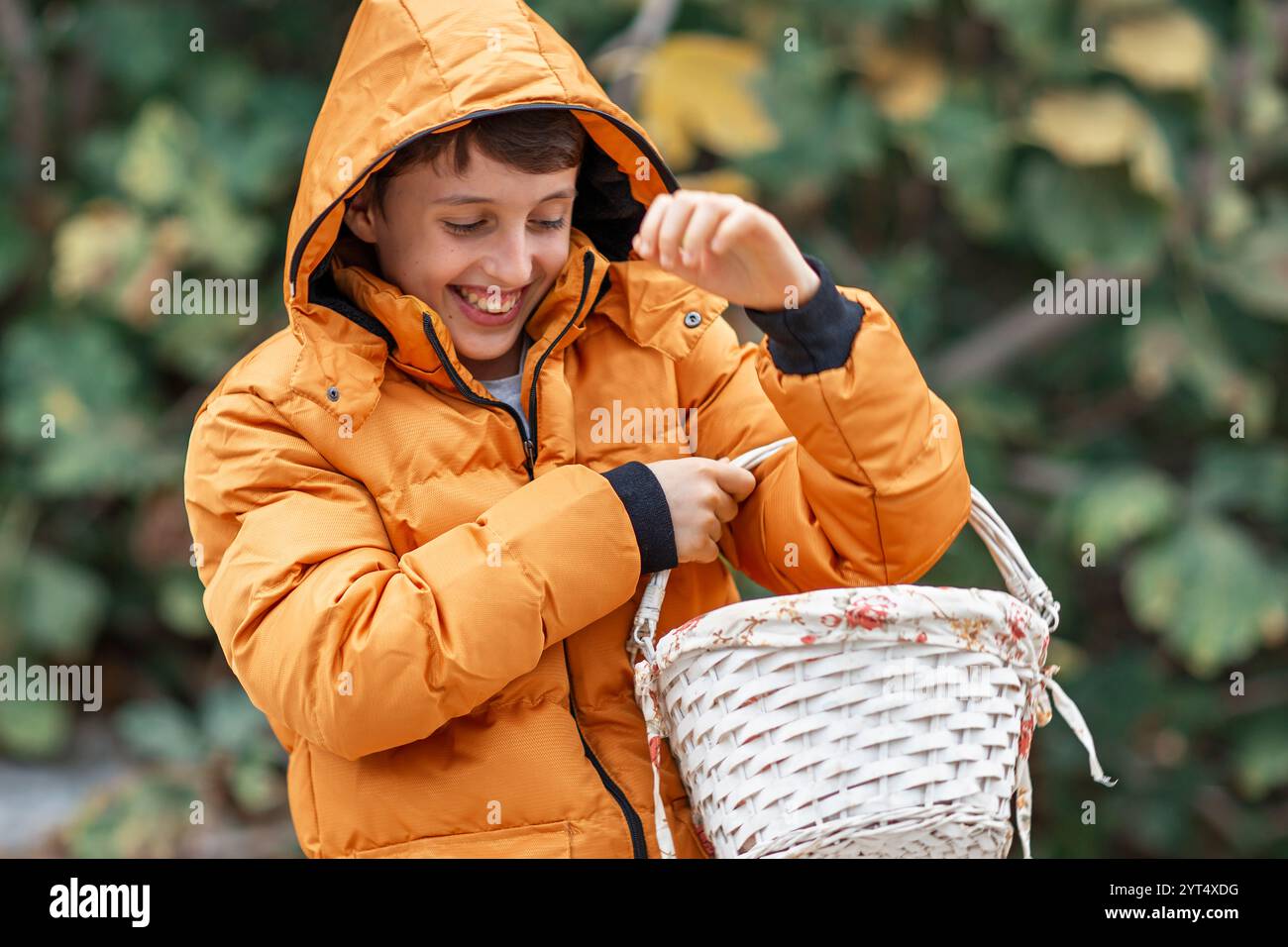 Junge in Winterjacke mit Korb und Lächeln Stockfoto