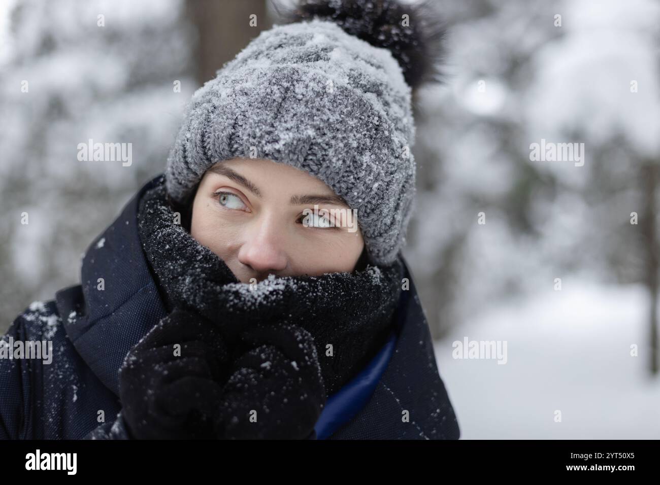 Porträt einer jungen Frau, die im Winterwald wegschaut Stockfoto
