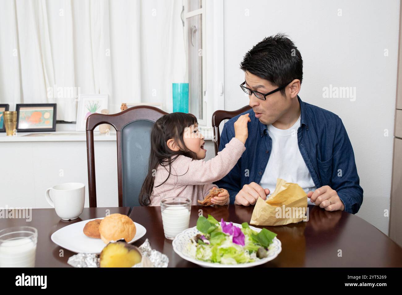Mädchen, das versucht, ihrem Vater Nahrung zu füttern Stockfoto