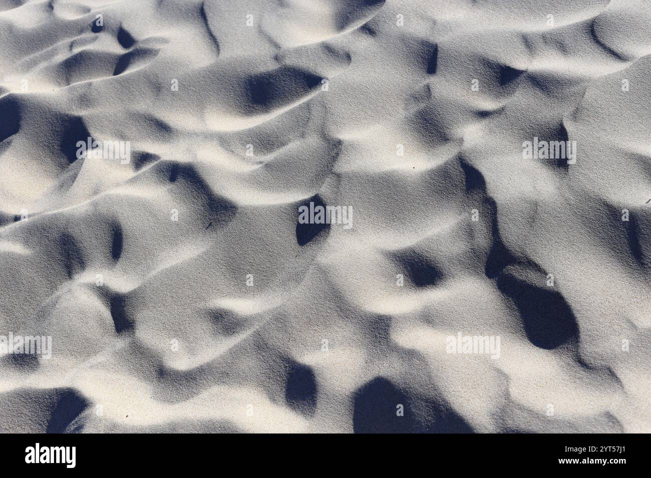 Eine Nahaufnahme der Sandstruktur an einem Strand, die die komplizierten Muster von Licht und Schatten zeigt. Das Spiel des Sonnenlichts hebt den subtilen Kamm hervor Stockfoto