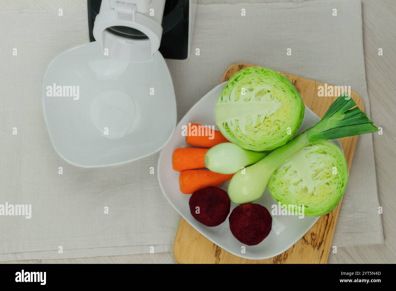 Kohl, Karotten, Rüben und Zwiebeln in der Nähe des Gemüseschneiders auf dem Küchentisch. Gehacktes Gemüse. Hausgemachte gesunde Lebensmittel. Gesunde Leitung. Stockfoto