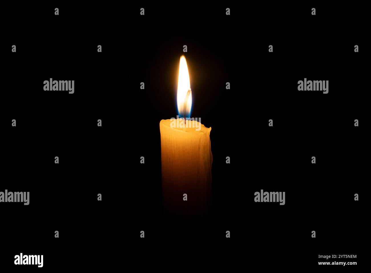 Eine orangene Kerze brennt im Dunkeln auf schwarzem Hintergrund. Das Konzept von Erinnerung und Trauer. Stockfoto