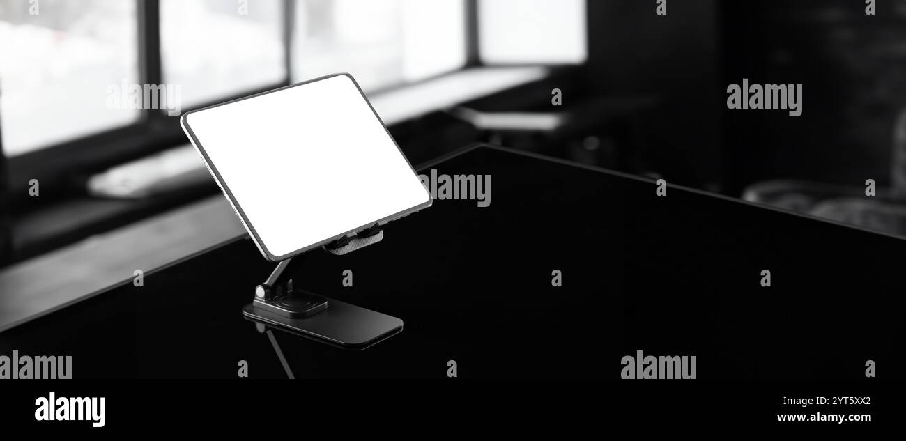 Ein schlankes iPad-Modell, das auf reflektierendem schwarzem Glas steht. Das minimalistische Design und die glatte Oberfläche unterstreichen die moderne Ästhetik des Tablets Stockfoto