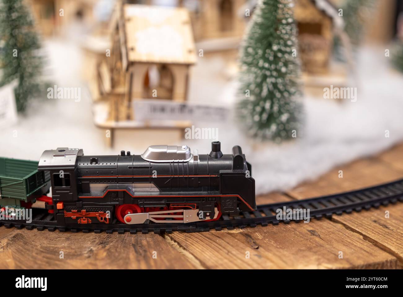 Spielzeugzug, der auf der Eisenbahntrasse mit winterlichem Landcape-Hintergrund und Weihnachtsbaum fährt Stockfoto
