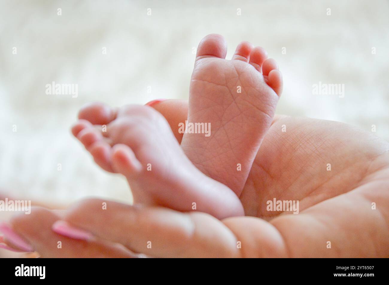 Neugeborene Babyfüße in der Hand der Mutter Stockfoto