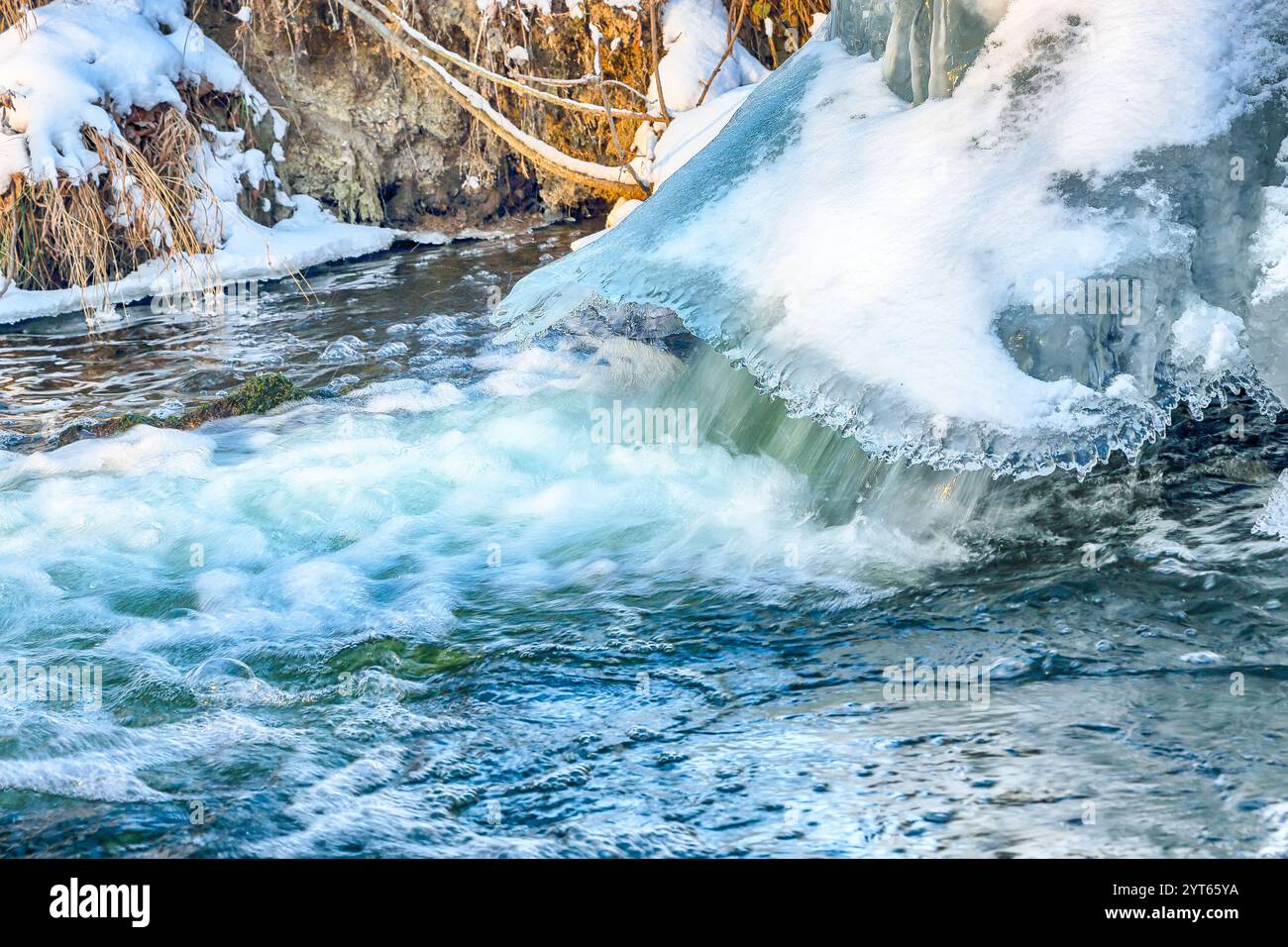 Landschaftsfoto eines nicht gefrorenen Flusses mit schneller Strömung und Stromschnellen an düsteren kalten Wintertagen. Winterlandschaft Stockfoto