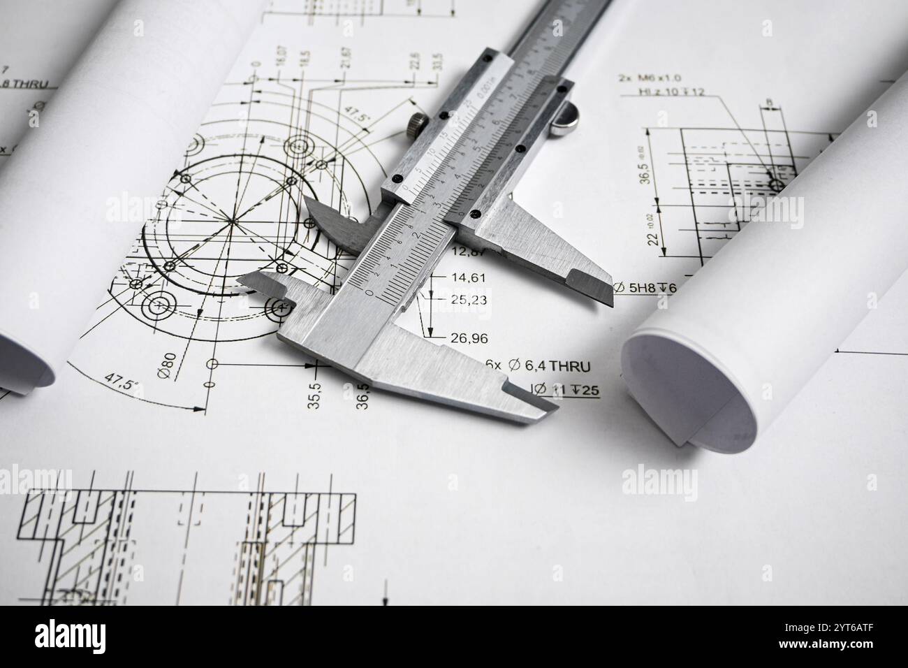 Der Messschieber liegt auf gerollten Blaupausen auf und unterstreicht die Bedeutung präziser Messungen in der Konstruktion und Konstruktion. Stockfoto