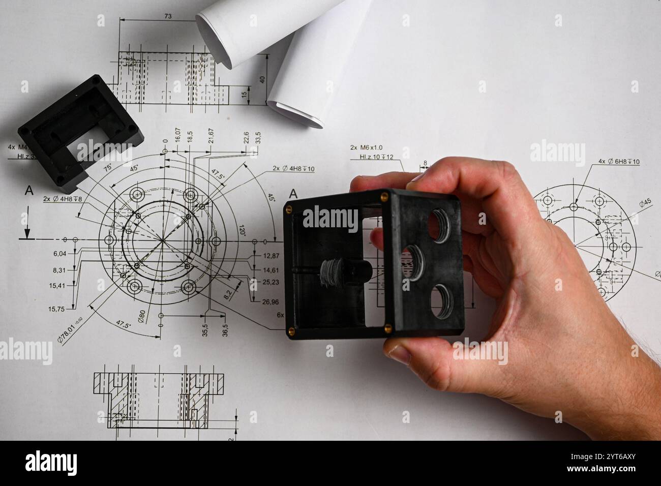 Ein Ingenieur untersucht einen 3D-gedruckten Prototyp und vergleicht ihn mit technischen Zeichnungen. Stockfoto