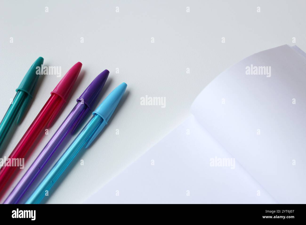 Tintenstift in vier coolen Farben und leeres Notizblock aus Papier mit Kopierraum für Bildungsbanner. Kreative Schreibwaren, Kunstunterricht, Schreibunterricht, zurück zur Schule. Stockfoto