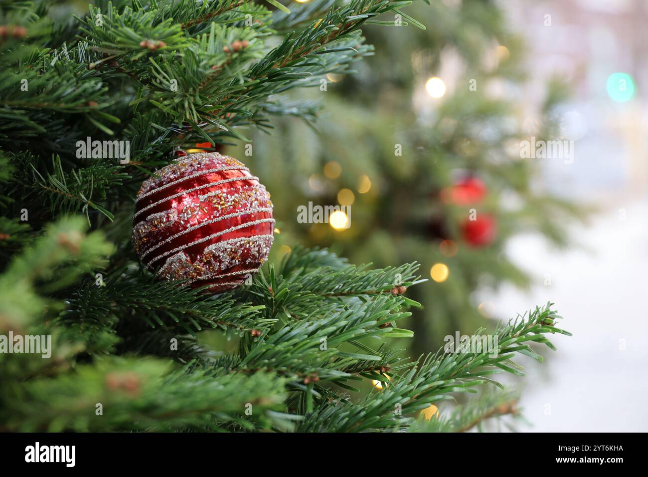 Neujahrsfeier in der Stadt, Weihnachtsbaum mit roter Spielzeugkugel auf verschwommenem Straßenhintergrund Stockfoto