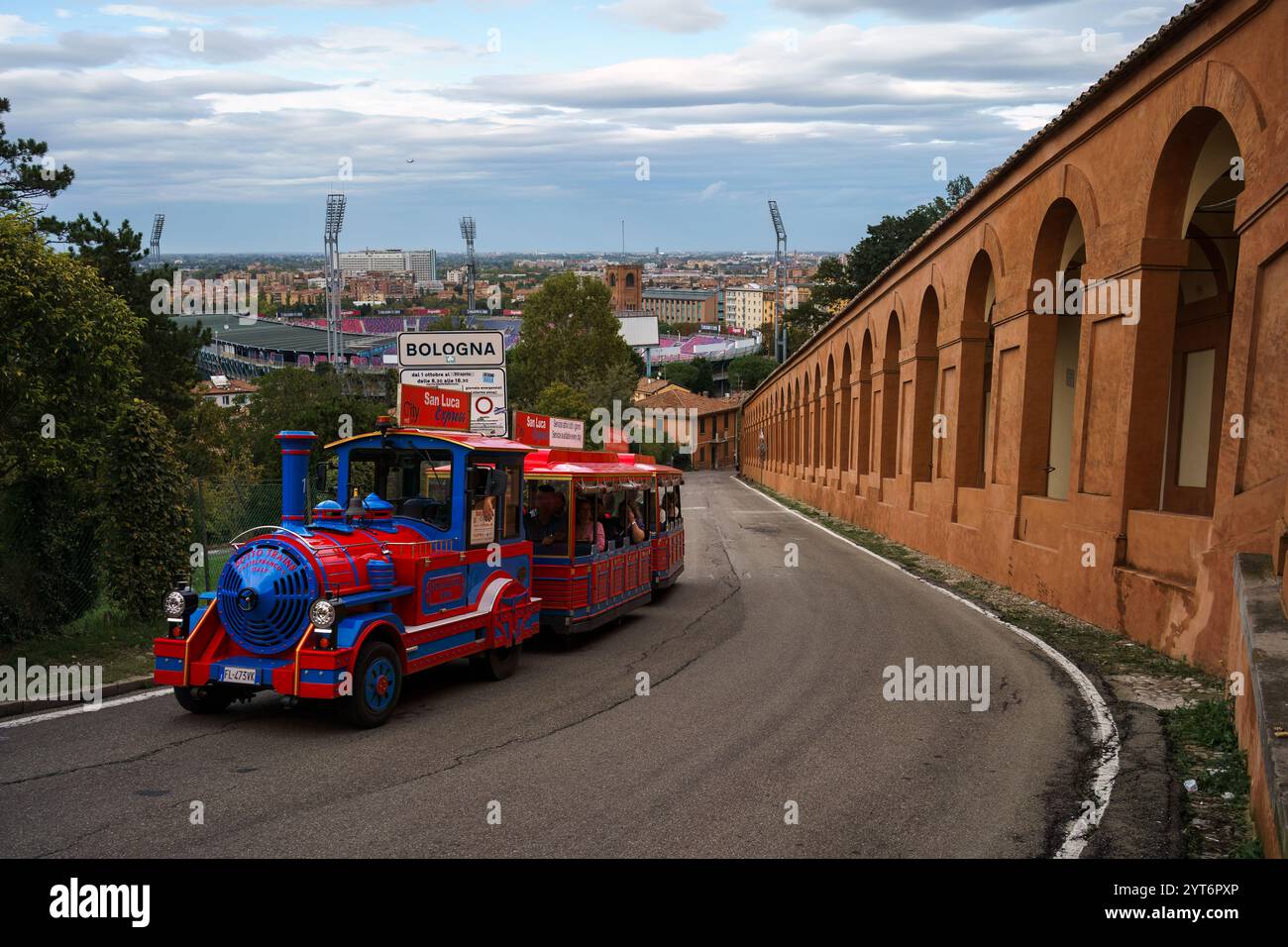 Bologna, Italien. 9. Oktober 2024 - farbenfroher Touristenzug San Luca Express entlang Portico di San Luca. Stockfoto