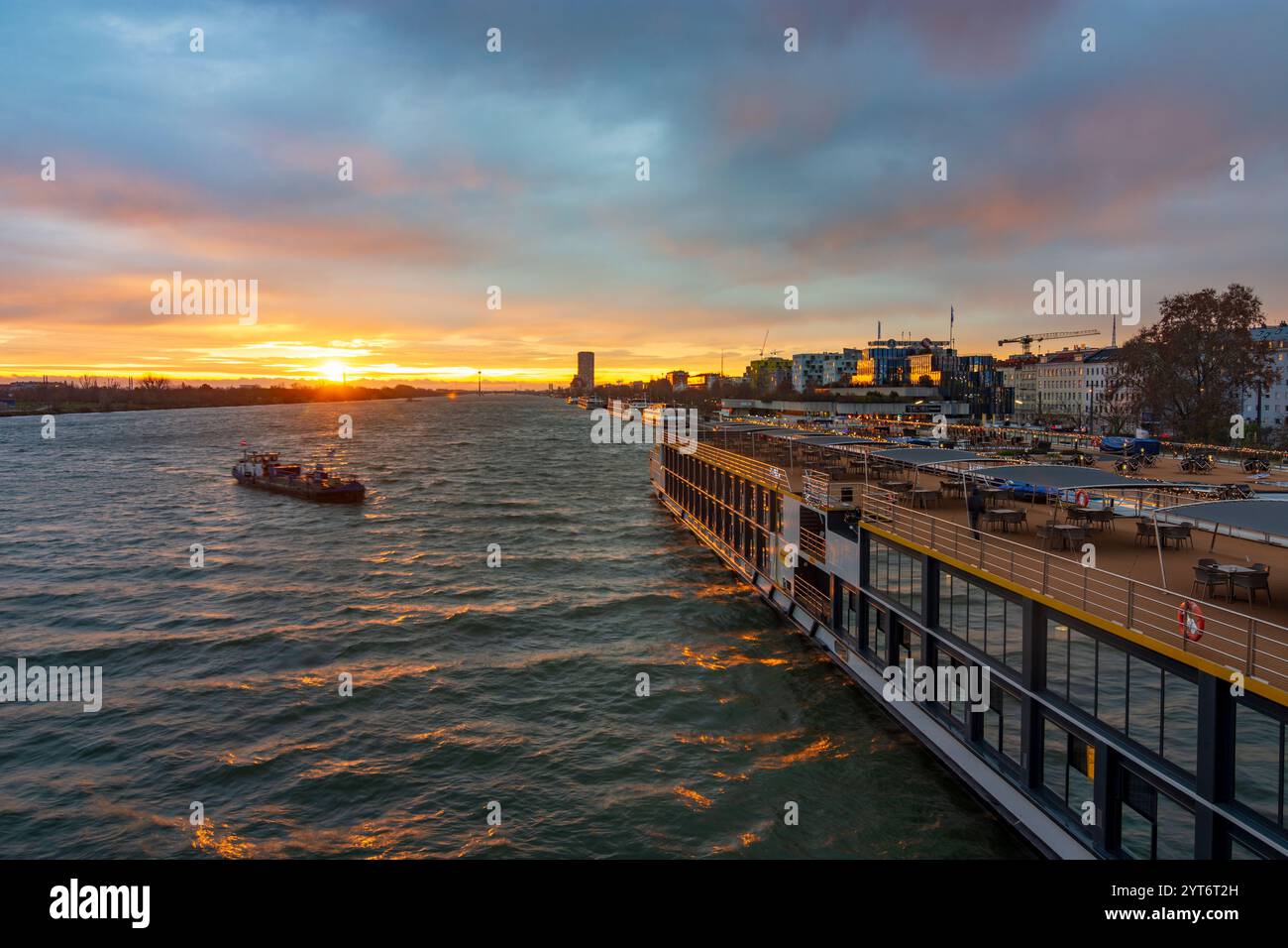 Wien: Sonnenaufgang auf der Donau, Kreuzfahrtschiffe an der Endbrücke Reichsbrücke, Bunkerschiff am Kreuzfahrtschiff 02. Leopoldstadt, Wien, Österreich Stockfoto