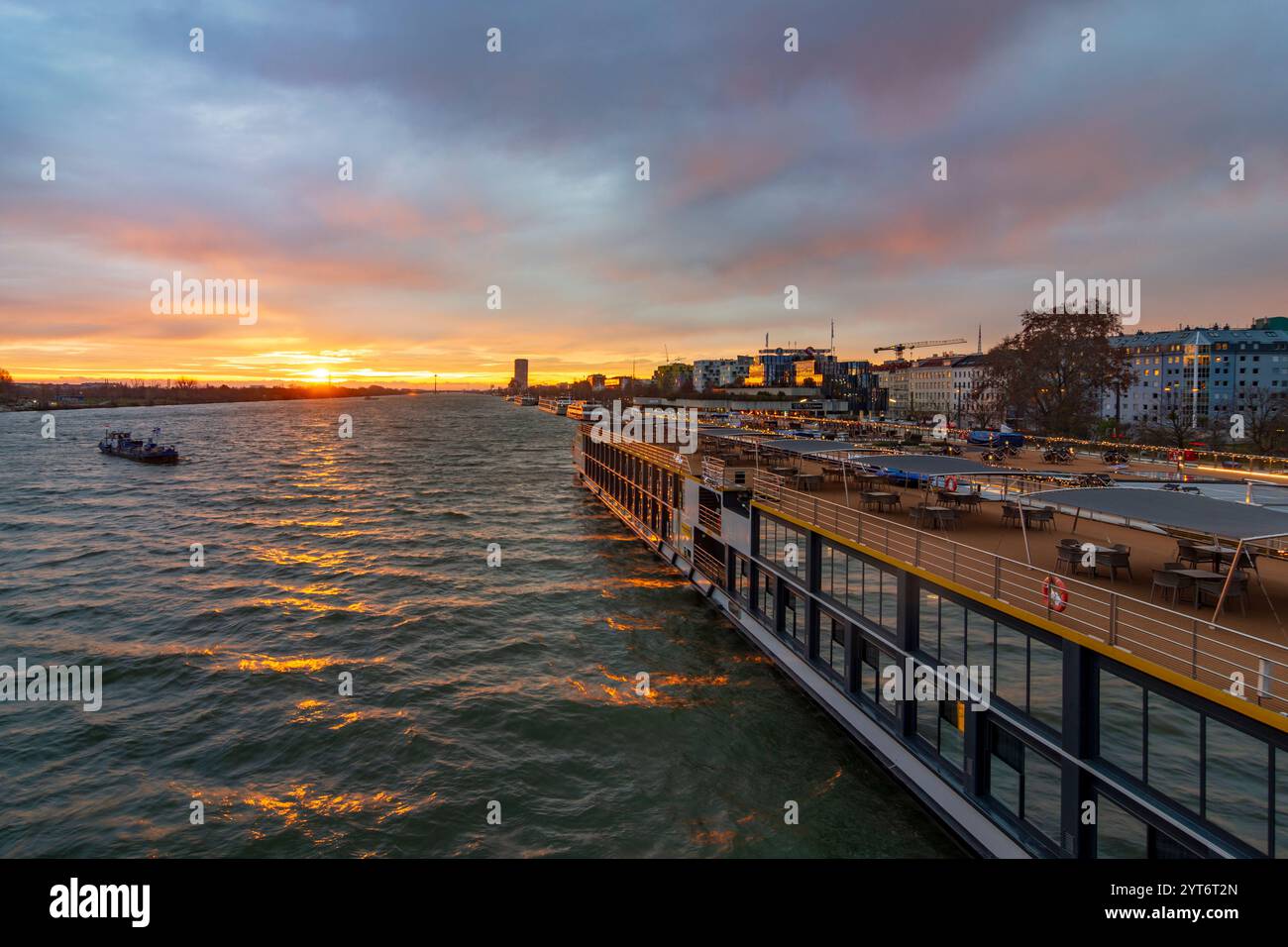 Wien: Sonnenaufgang auf der Donau, Kreuzfahrtschiffe an der Endbrücke Reichsbrücke, Bunkerschiff am Kreuzfahrtschiff 02. Leopoldstadt, Wien, Österreich Stockfoto