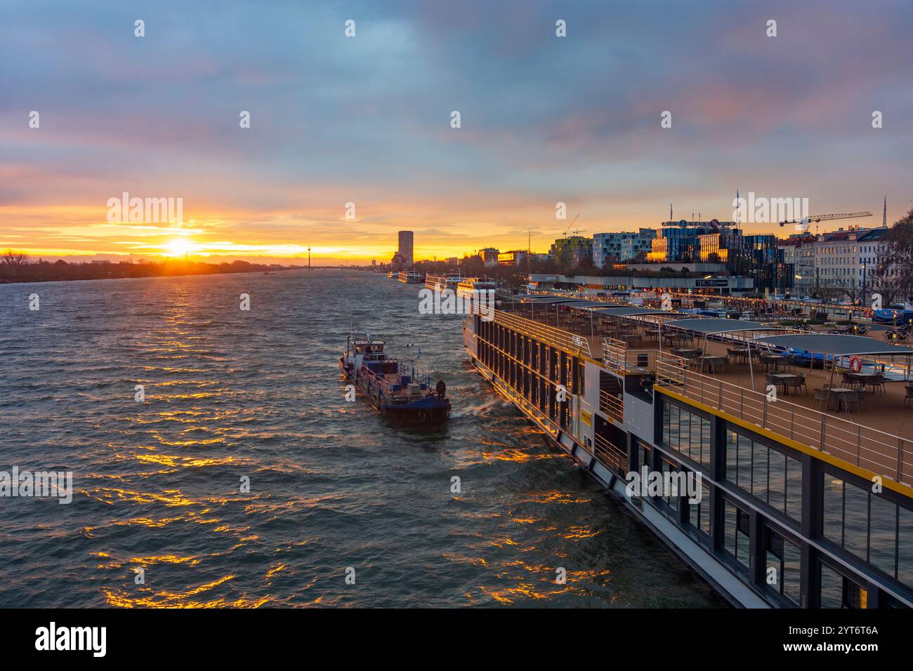 Wien: Sonnenaufgang auf der Donau, Kreuzfahrtschiffe an der Endbrücke Reichsbrücke, Bunkerschiff am Kreuzfahrtschiff 02. Leopoldstadt, Wien, Österreich Stockfoto