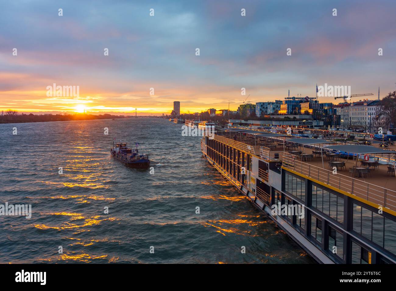 Wien: Sonnenaufgang auf der Donau, Kreuzfahrtschiffe an der Endbrücke Reichsbrücke, Bunkerschiff am Kreuzfahrtschiff 02. Leopoldstadt, Wien, Österreich Stockfoto