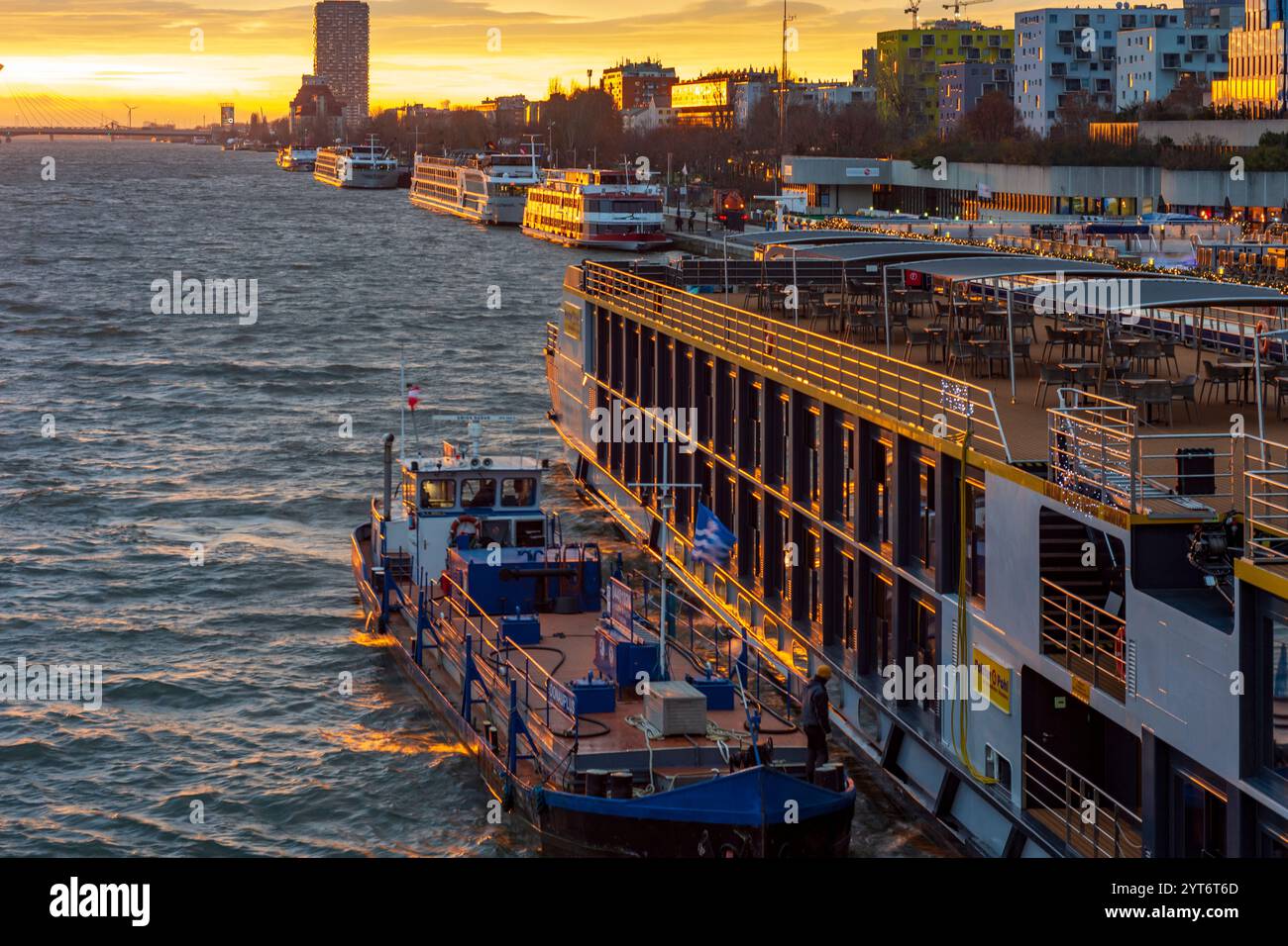 Wien: Sonnenaufgang auf der Donau, Kreuzfahrtschiffe an der Endbrücke Reichsbrücke, Bunkerschiff am Kreuzfahrtschiff 02. Leopoldstadt, Wien, Österreich Stockfoto