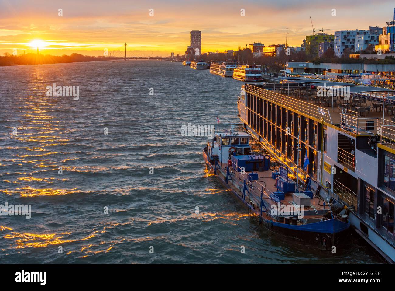 Wien: Sonnenaufgang auf der Donau, Kreuzfahrtschiffe an der Endbrücke Reichsbrücke, Bunkerschiff am Kreuzfahrtschiff 02. Leopoldstadt, Wien, Österreich Stockfoto