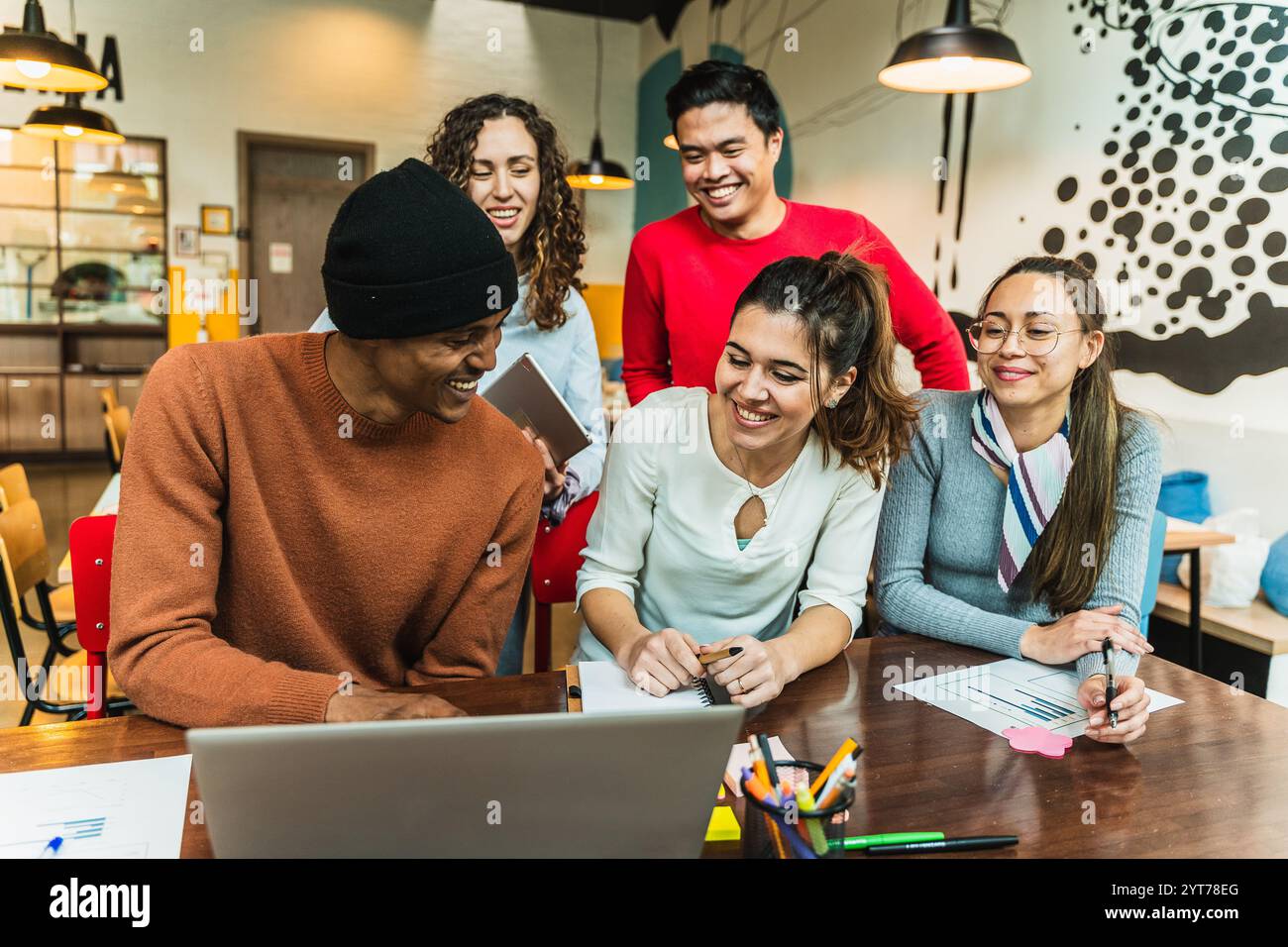 Ein vielfältiges Team von Kollegen arbeitet an einem Projekt zusammen, nutzt einen Laptop und teilt Ideen in einer modernen Büroumgebung Stockfoto