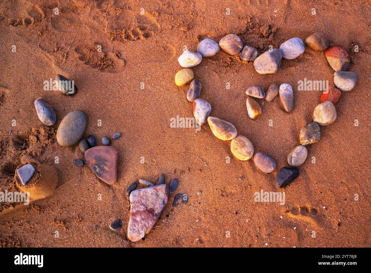 Gestalt Herz aus Kieselstein auf Sand, universelles Symbol der Liebe, Nahaufnahme. Stockfoto