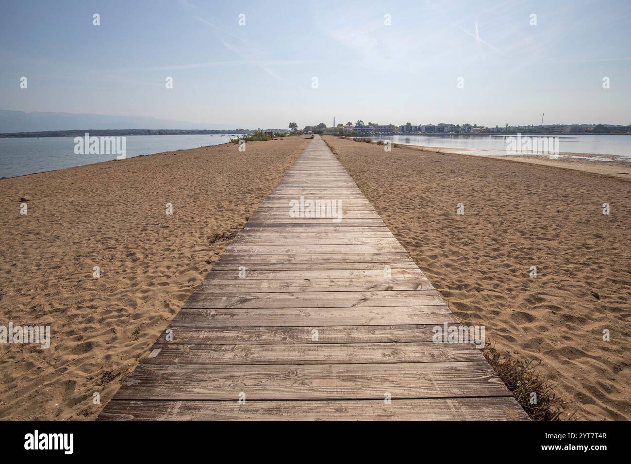 Ein Strand, der auf beiden Seiten vom Meer umgeben ist. Ein Holzsteg führt entlang des Sandstrandes in der Mitte. Naturschauspiel einer mediterranen Landschaft, Plaua edrijac, Nin, Zadar, Dalmatien, Kroatien Stockfoto