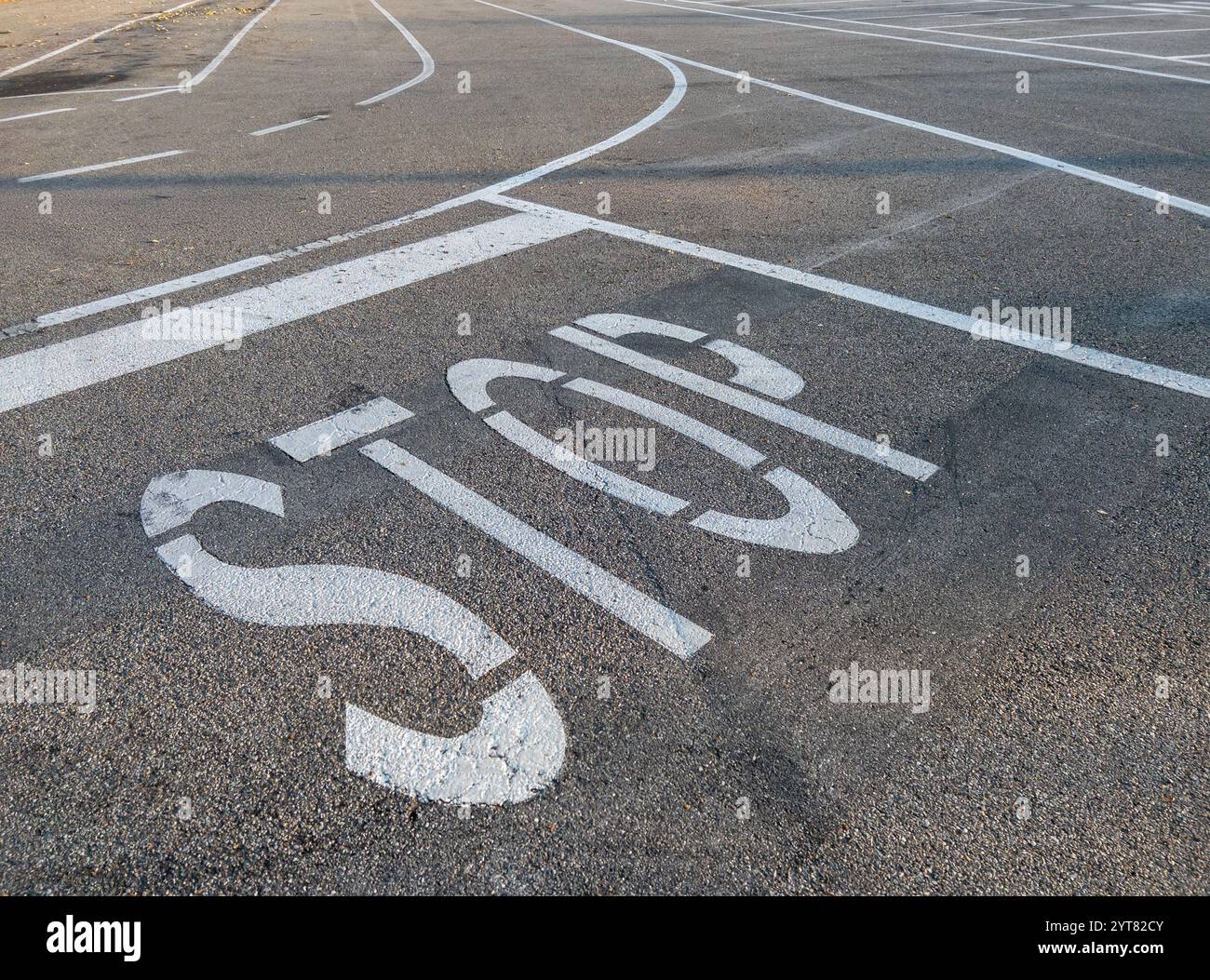 Stoppschild weiß auf dem Straßenasphalt mit horizontalen Schildern weiß lackierte Streifen auf der Straße Stockfoto