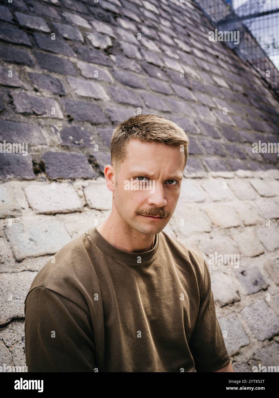 Ein Mann, der sich an eine Mauer in der Stadt lehnt Stockfoto