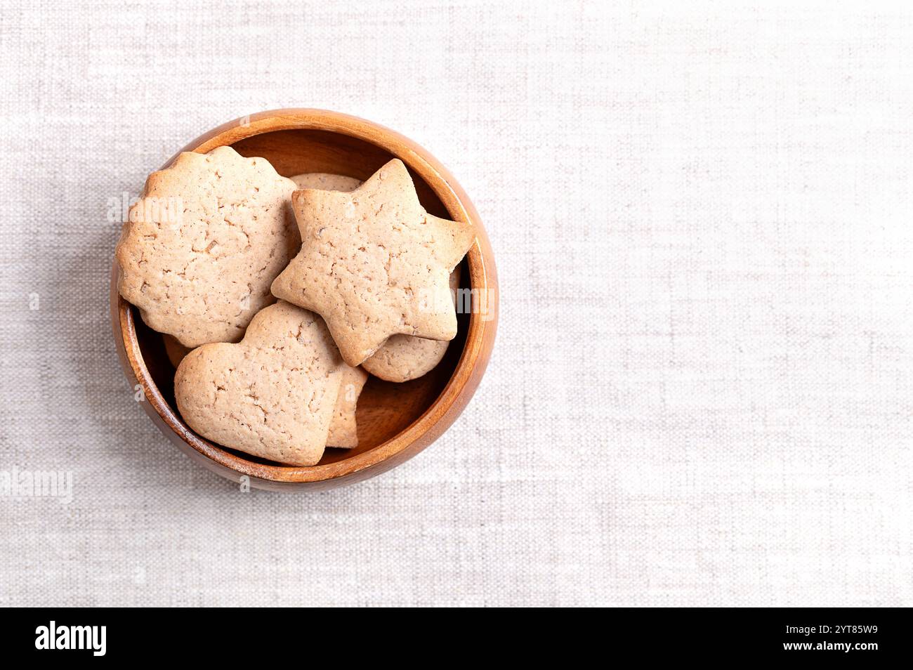 Hausgemachte Lebkuchenkekse in einer Holzschale auf Leinenstoff, mit leerem Platz für Text. Süße, hellbraune und flache Backwaren zu Weihnachten. Stockfoto